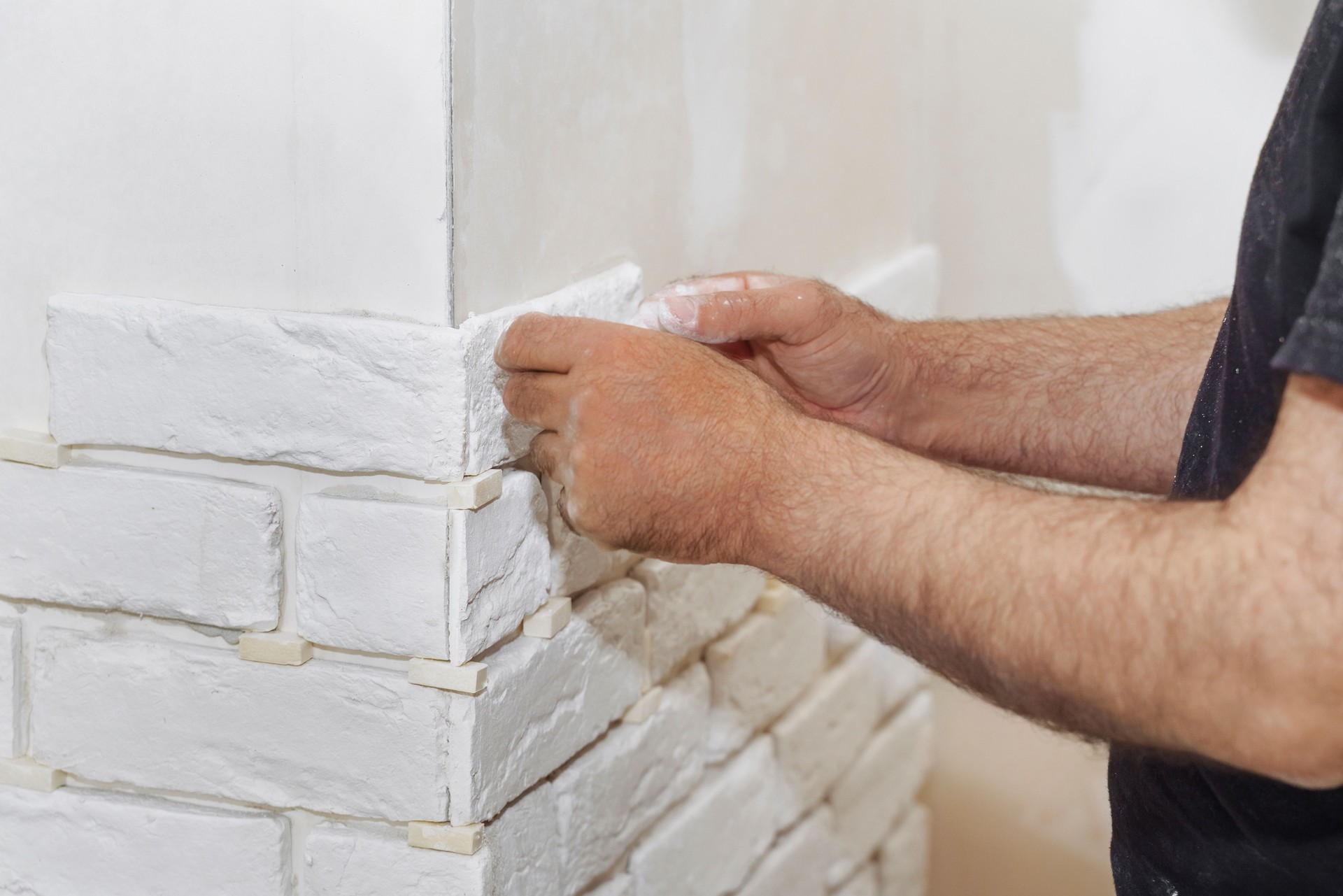 Professional Builder gluing decorative tile on wall. Worker mounts decorative Brick on Wall